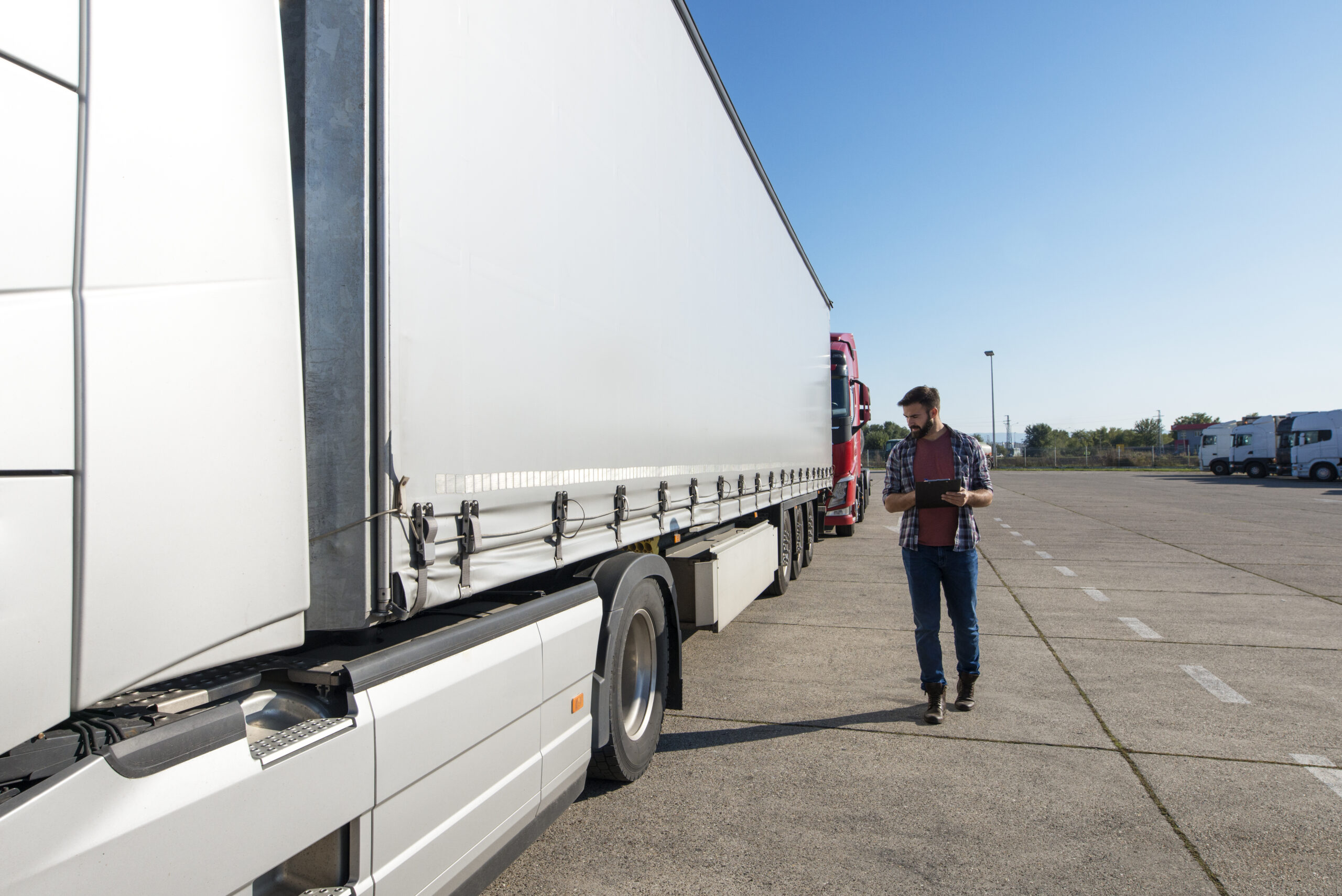 Truck driver inspecting vehicle, trailer and tires before driving.